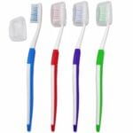 Four adult manual toothbrushes with coloured grips and travel covers to clip over the brush head.
